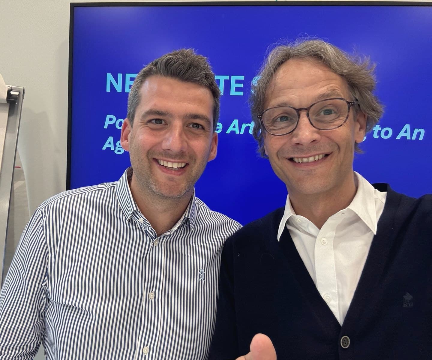 Deux membres de l'équipe, souriants, devant l'écran d'une session de négociation.