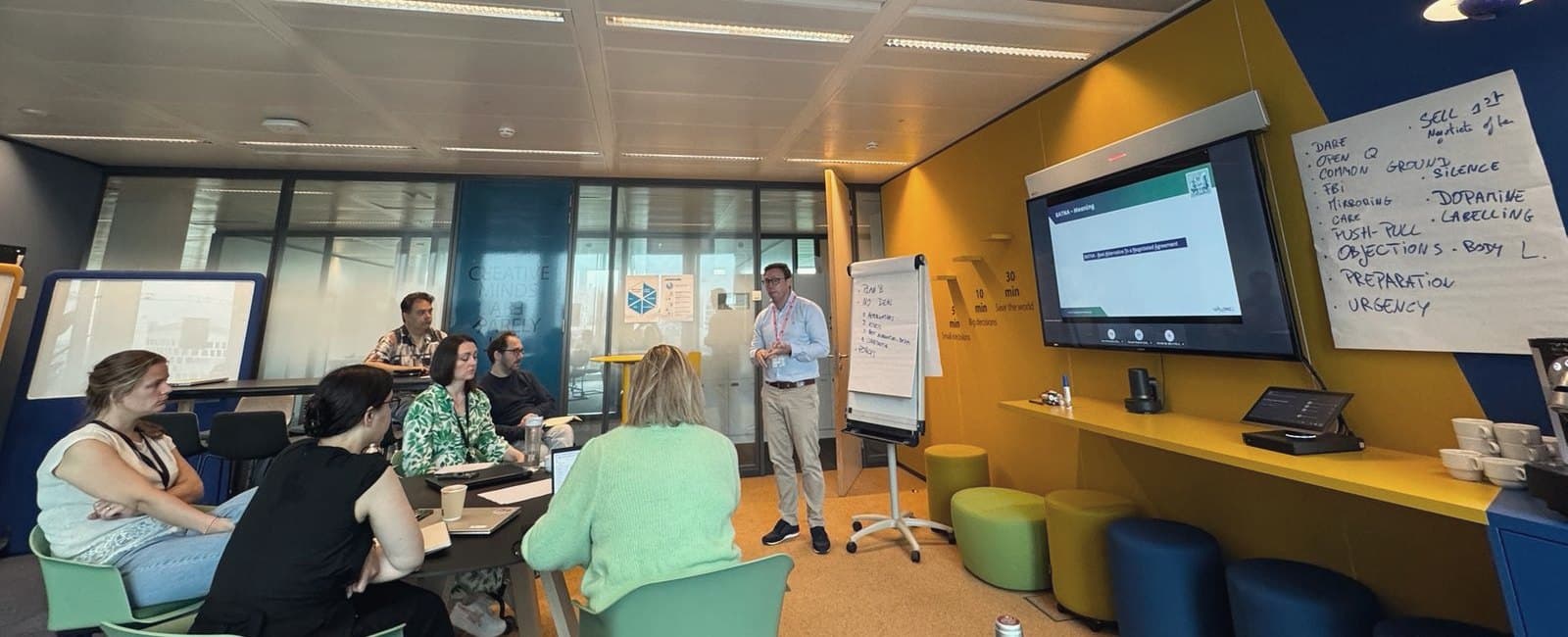 Une formation à la négociation en entreprise : le formateur au tableau, les participants autour de la table.